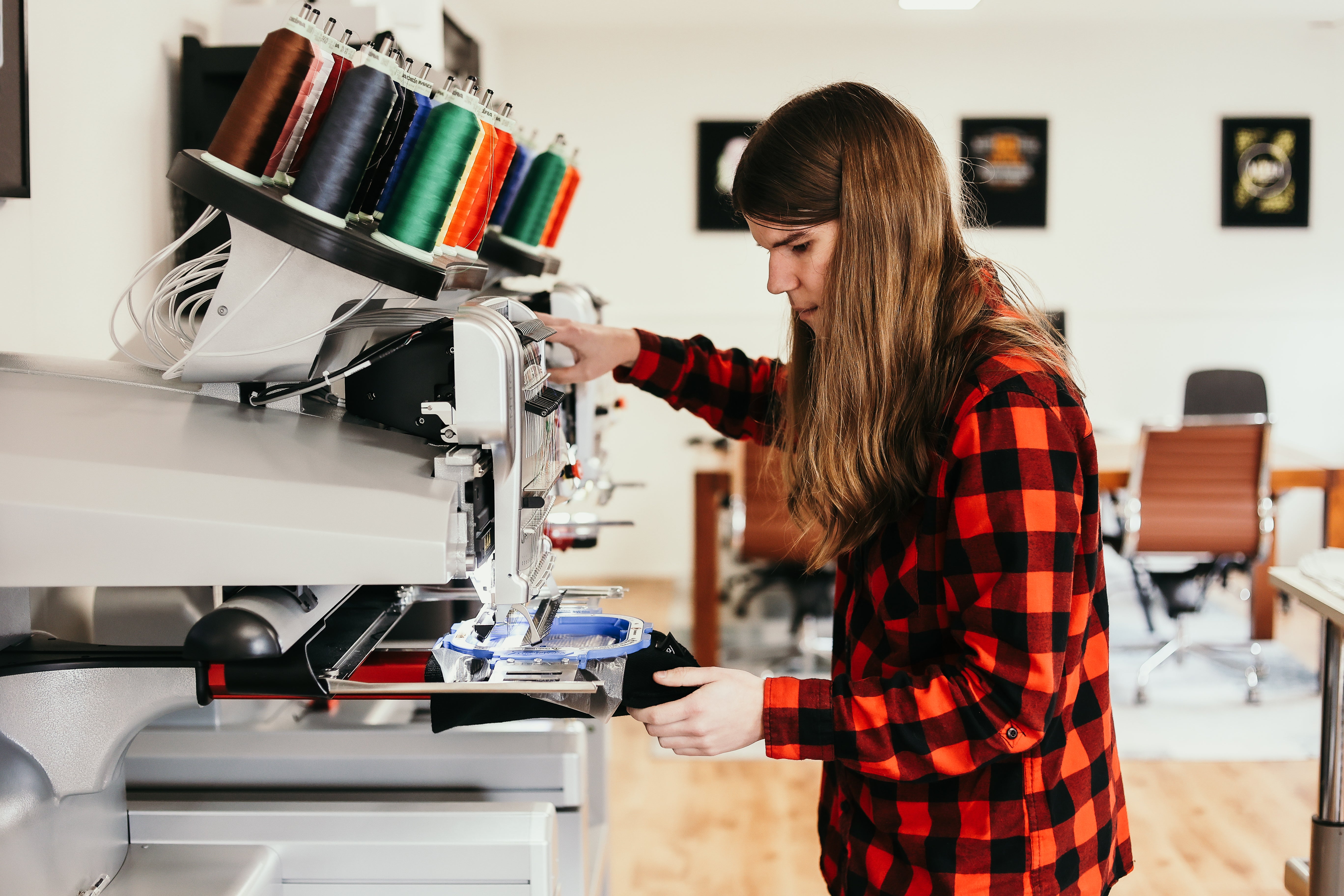 Kelly werkt aan een borduurmachine bij Red Dot Media in Slagharen, gespecialiseerd in bedrukte en geborduurde producten voor bedrijven en verenigingen.